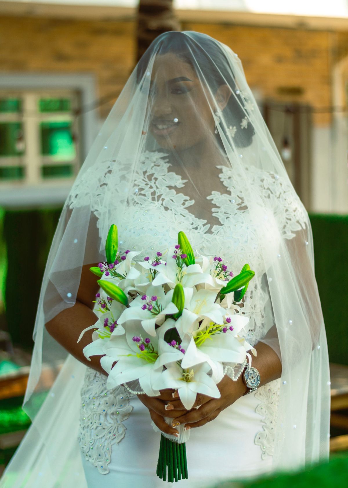 Classic white wedding bride in lace gown and veil holding a lily bouquet