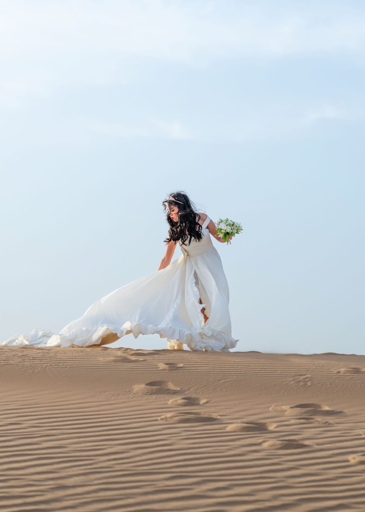 Destination bride in an elegant gown on golden desert dunes