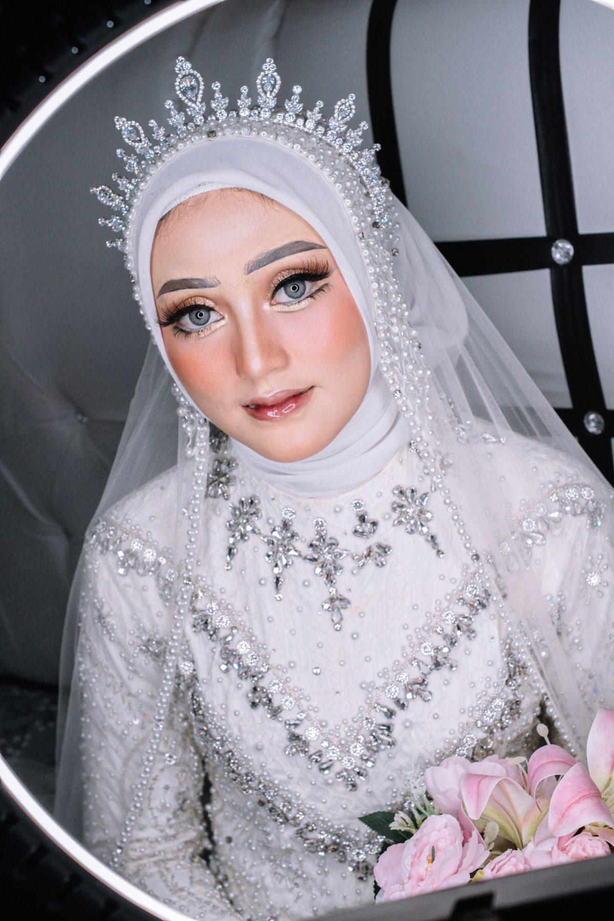 Muslim bride in a sparkling gown with soft luxurious makeup holding a pink bouquet